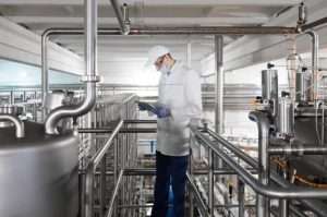 Technologist Stands With A Tablet In The Shop At The Dairy Plant